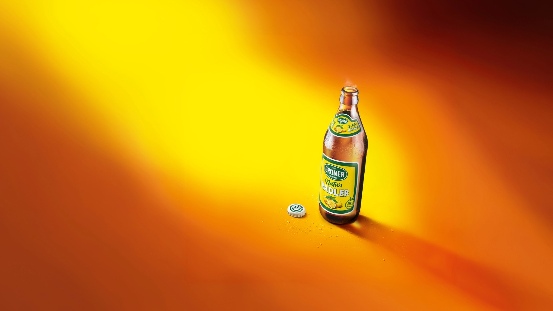 Eine betaute Flasche Grüner Natur Radler vor gelb-orangenem Hintergrund. 