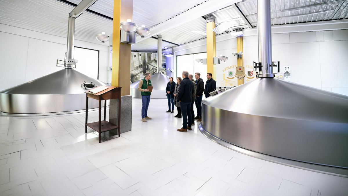 Besucher und ein Brauereiführer stehen zwischen Sudkesseln im Zwei-Städte-Sudhaus.